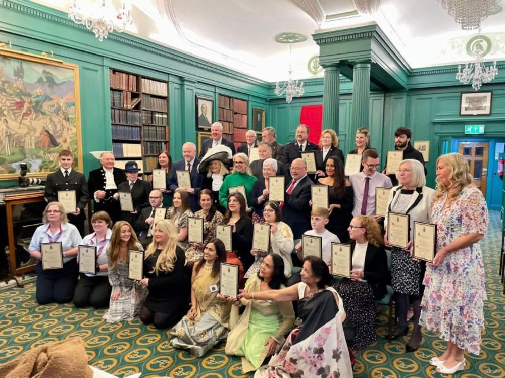 Group of people holding certificates awarded by the High Sheriff of Merseyside