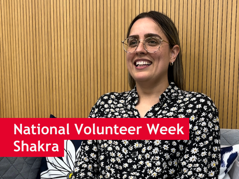 Shakra, a volunteer at Strawberry Field, sat on a sofa with a big smile. There is text overlay which reads 'National Volunteer Week, Shakra'
