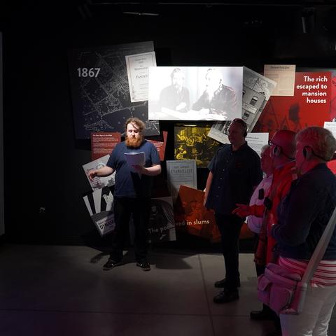 People stand inside exhibition space about John Lennon
